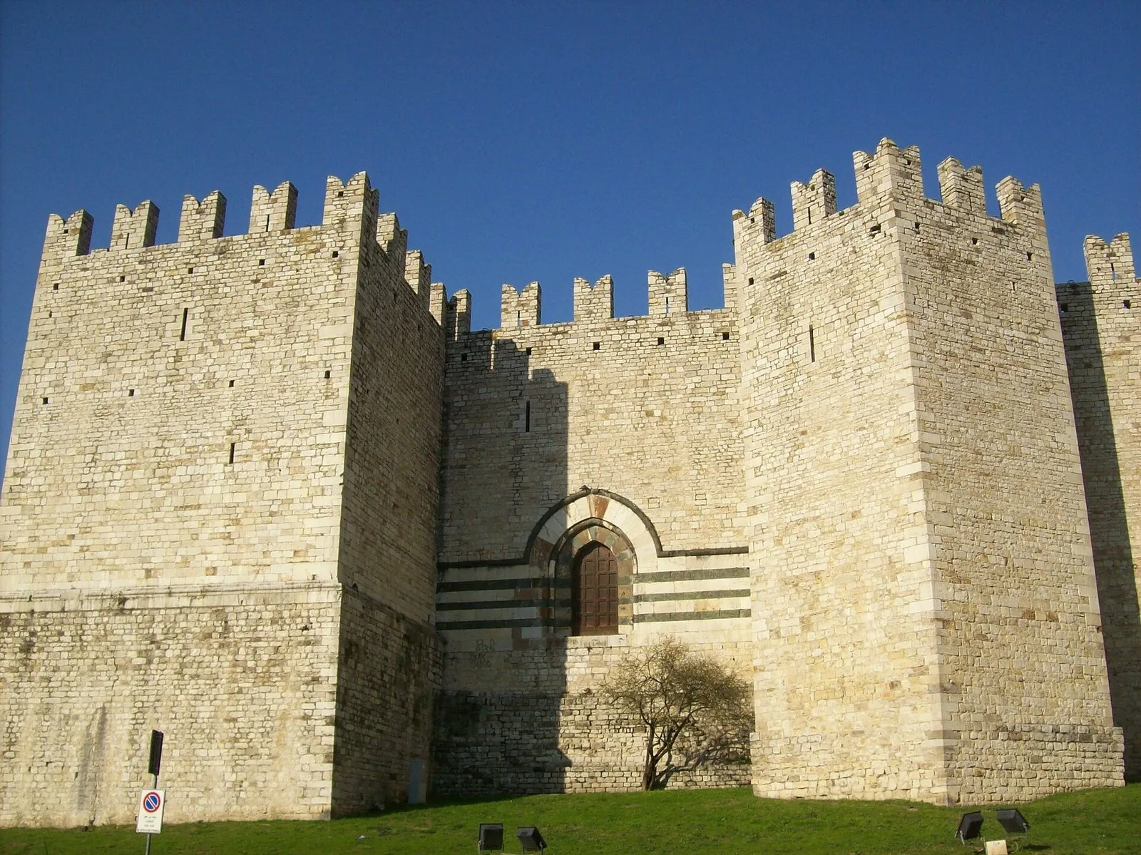 Le mura merlate e le torri in pietra chiara del Castello dell'Imperatore a Prato, con il portale a fasce bianche e verdi